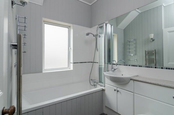 BATHROOM: White suite comprising tongue and groove panelled bath with shower attachment and shower screen, vanity unit, low flush wc, timber tongue and groove