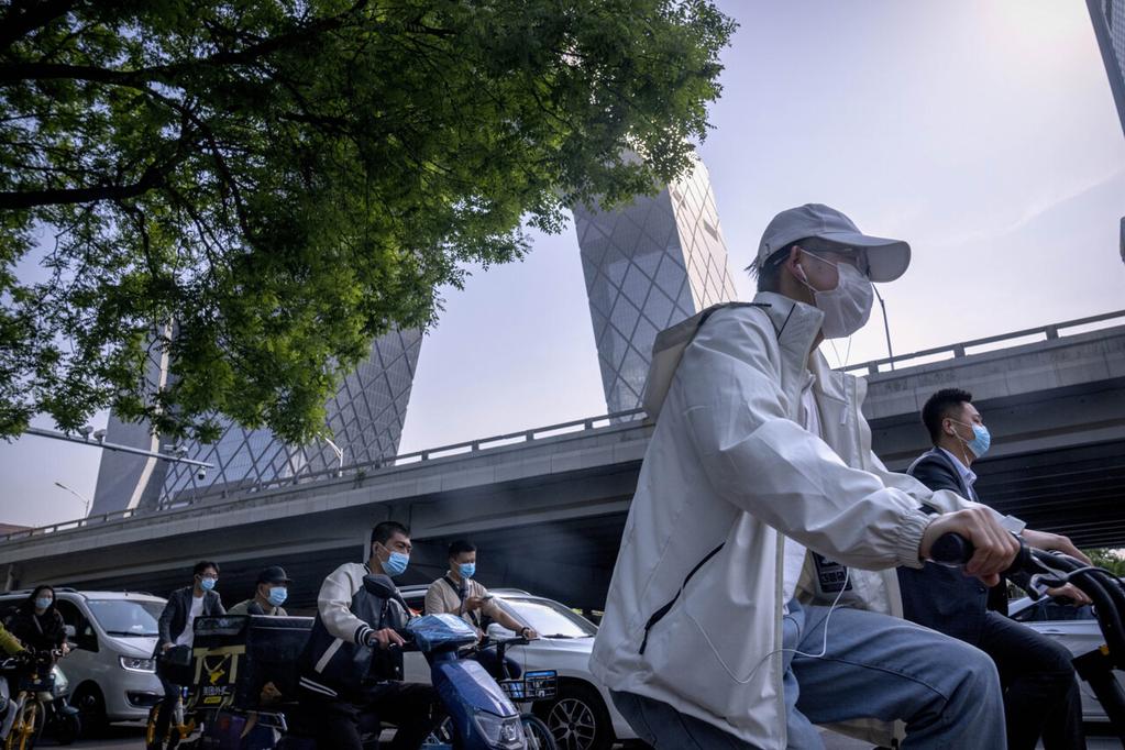 Commuters wearing face masks wait at an intersection in the central business district in Beijing, Thursday, May 5, arrivals from overseas.